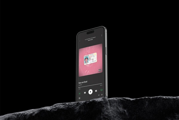 Photographie d'un téléphone posé sur un rocher avec une pochette d'album rose sur l'écran par John Bertolini