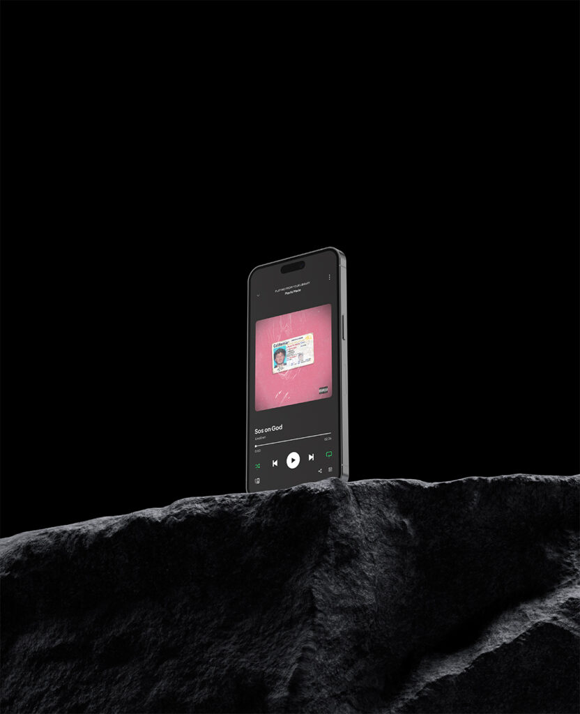 Photographie d'un téléphone posé sur un rocher avec une pochette d'album rose sur l'écran par John Bertolini